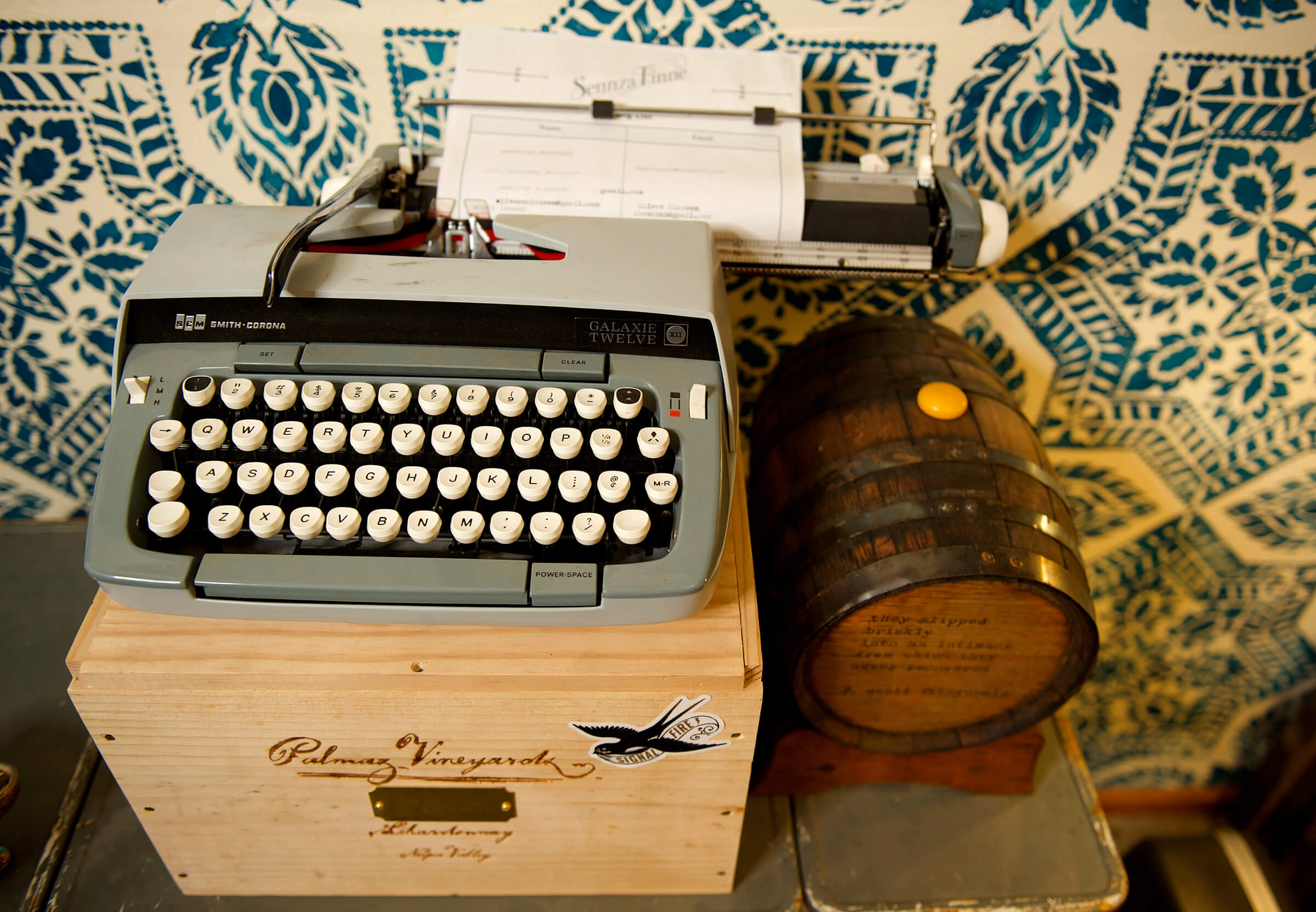 Vintage typewriter on a wooden box with a patterned fabric background